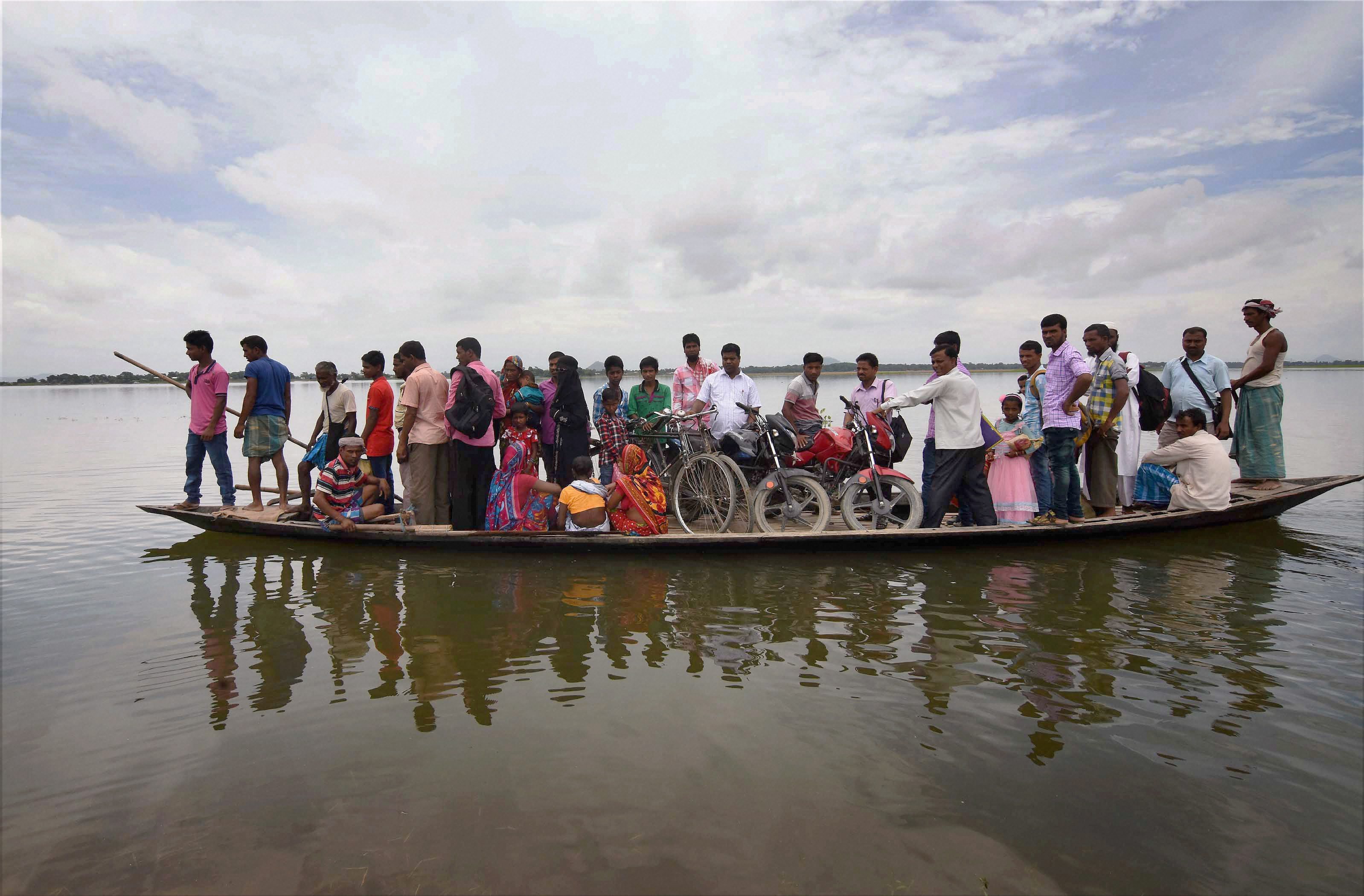 Morigaon: Villagers sit on a boat as they are transported to safety after their houses got submerged in flood waters at Balimukh village in Morigaon district of Assam. PTI Photo(PTI7_1_2017_000189B)