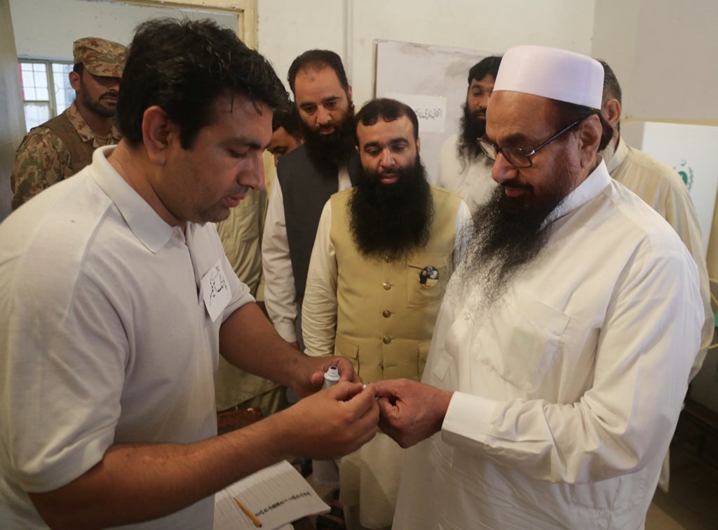 Lahore: An election officer marks a thumb of Hafiz Saeed, right, head of the Pakistani religious party Jamaat-ud-Dawa, at polling station in Lahore, Pakistan, Wednesday, July 25, 2018. After an acrimonious campaign, polls opened in Pakistan on Wednesday to elect the country's third straight civilian government. AP/PTI(AP7_25_2018_000071B)