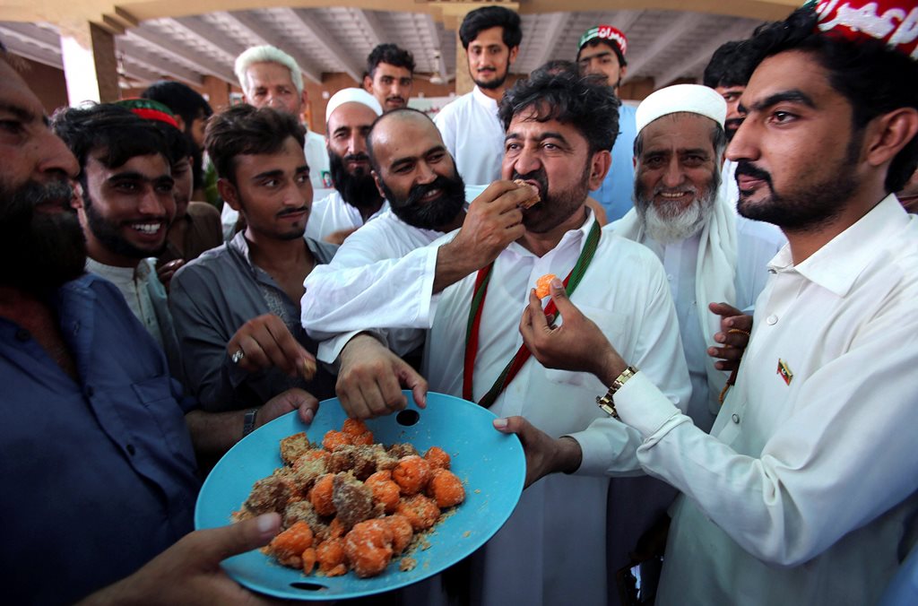 Peshawar ;Supporters of Pakistani politician Imran Khan, chief of Pakistan Tehreek-e-Insaf party, offer sweets to each other to celebrate the victory of their party candidate, in Peshawar, Pakistan, Thursday, July 26, 2018. Pakistan's former cricket star Imran Khan and his party were maintaining a commanding lead Thursday amid slow and tedious counting of ballots from a historic election. Election officials said an official count confirming Pakistan's next government was expected later in the evening. AP/PTI(AP7_26_2018_000194B)
