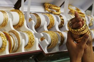 A customer tries gold bangles inside a jewellery showroom at Noida in the northern Indian state of Uttar Pradesh in this April 21, 2011 file photo. India's passion for gold is putting such a strain on state finances that the government may slap higher import taxes on the precious metal, but demand buoyed by heady inflation and meagre savings will blunt the impact of any rise in duties as reported January 16, 2013. REUTERS/Parivartan Sharma)