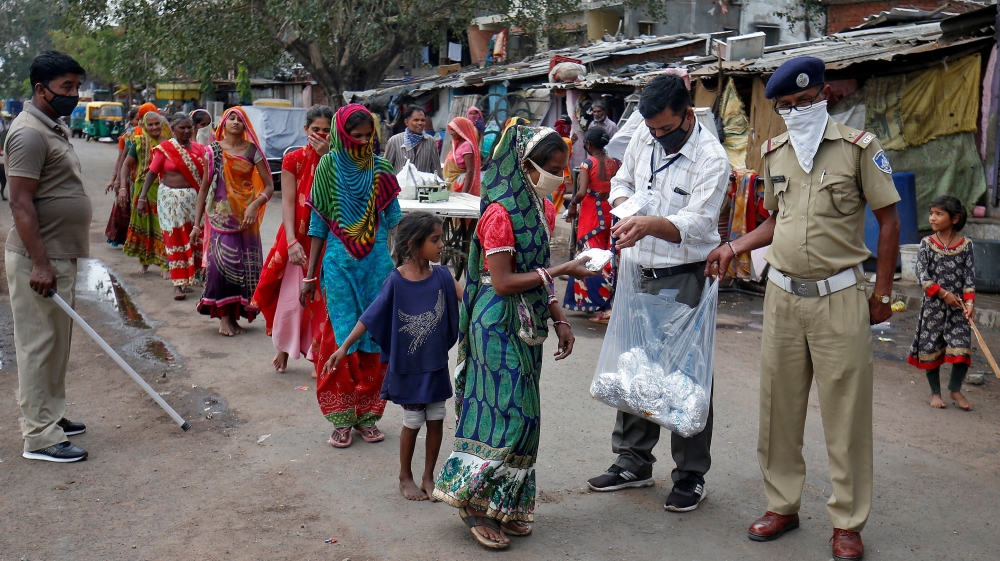 Slum dwellers in Ahmedabad receive free food packets during a 21-day nationwide lockdown [Amit Dave/Reuters]