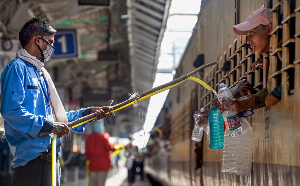 Jabalpur: Railway official provides drinking water from a distance to migrants travelling by a train to their native places, during the ongoing nationwide COVID-19 lockdown, at a railway station in Jabalpur, Wednesday, May 27, 2020. (PTI Photo) (PTI27-05-2020 000149B)(PTI27-05-2020 000198B)