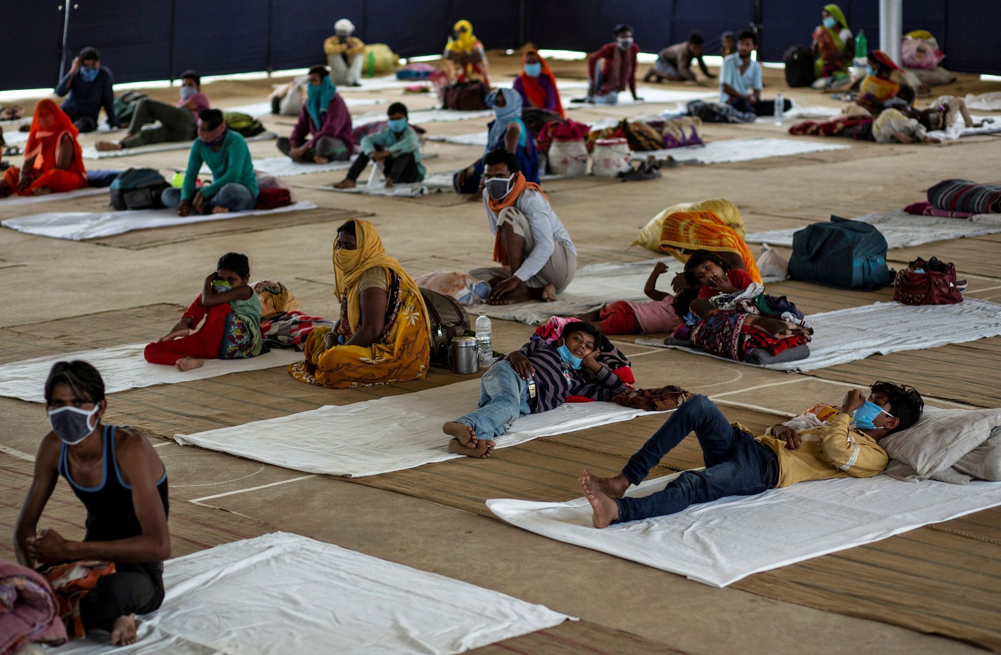 Migrant workers and their families rest inside a shelter managed by Indian Red Cross Society volunteers, during a nationwide lockdown to slow the spreading of the coronavirus disease (COVID-19), in Faridabad, India, April 14, 2020. REUTERS/Danish Siddiqui 