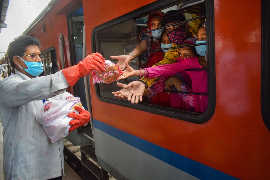 Prayagraj: A railway staff member distributes food packets among migrants sitting in Shramik Special train to reach their native places, during ongoing COVID-19 lockdown, at Prayagraj Railway Station, Sunday, May 31, 2020. (PTI Photo)(PTI31-05-2020_000074B)