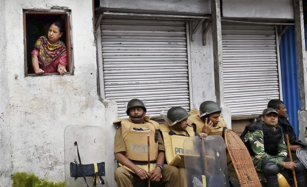 Darjeeling: Security personnel guard sit as woman looks out of window in Darjeeling on Sunday. PTI Photo by Ashok Bhaumik(PTI6_18_2017_000150B)