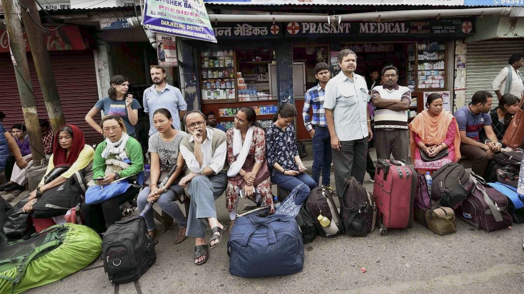 Darjeeling: Stranded tourists wait at a bus stand during the indefinite strike called by Gorkha Janamukti Morcha, in Darjeeling on Monday. PTI Photo by Ashok Bhaumik (PTI6_19_2017_000076B)