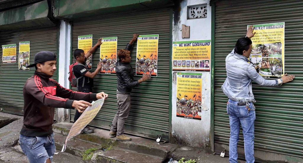 Darjeeling: Activists of GJM paste the party posters on the shutters of close shops during GJM indefinite strike near DM office in Darjeeling on Wednesday. PTI Photo by Ashok Bhaumik (PTI6_21_2017_000360B)