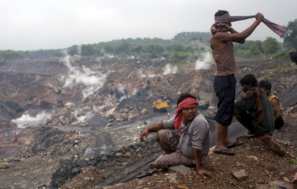 Workers sit atop an open cast coal field at Dhanbad district in Jharkhand, India, in this September 18, 2012 file photo. Photo Reuters