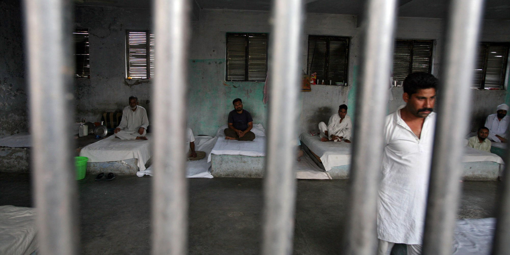 Inmates rest behind bars in a barrack at Kotbhalwal central jail in Jammu May 18, 2011. Jail authorities have formed a 20-member pipe band of a team of prisoners who are being trained to play and perform musical instruments. Once the band is ready, they will be sent to perform at weddings and other social functions, a jail superintendent said. The main aim of creating the pipe band is to develop relations of these prisoners with the rest of the outside world and to involve them in various social functions so as to change their mindset, the superintendent added. Picture taken May 18, 2011. REUTERS/Mukesh Gupta (INDIAN-ADMINISTERED KASHMIR - Tags: CRIME LAW SOCIETY ENTERTAINMENT)