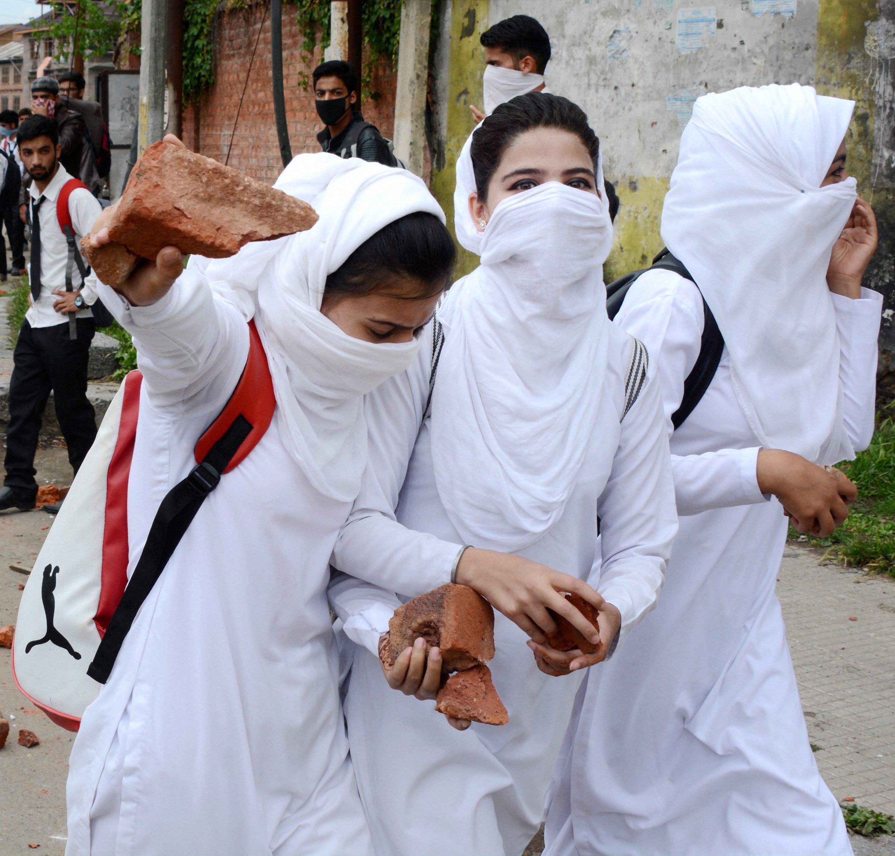 Srinagar: Girl Students holding stones to throw it on police during fresh clashes between students Police,Outside Gandhi College in Srinagar on Monday. PTI Photo(PTI5_22_2017_000174B)