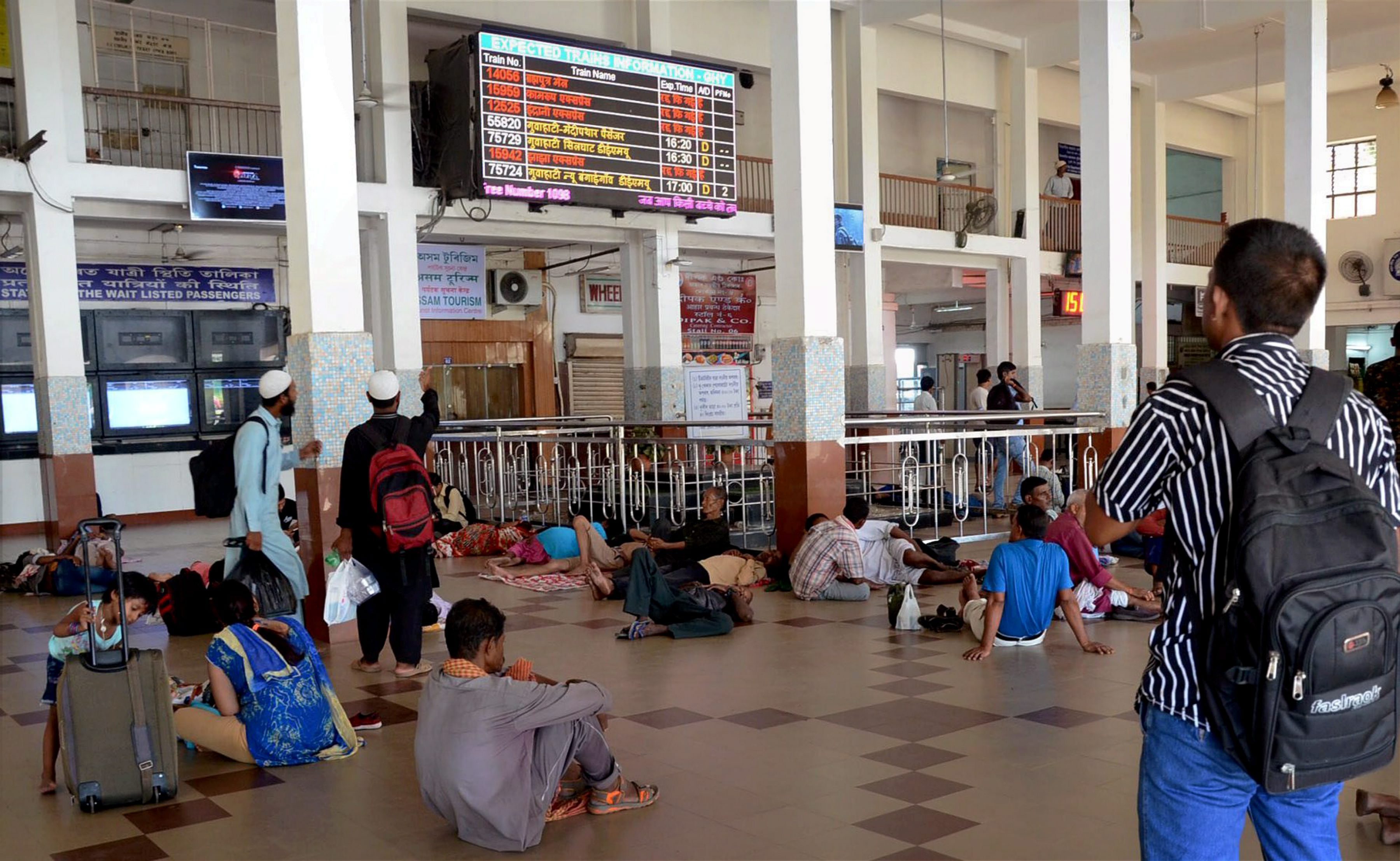 Guwahati: Passengers looking at the screen displaying the schedules of the trains at Guwahati Railway Station on Thursday: Major trains were cancelled due to floods in Assam. PTI Photo (PTI8_17_2017_000138B)