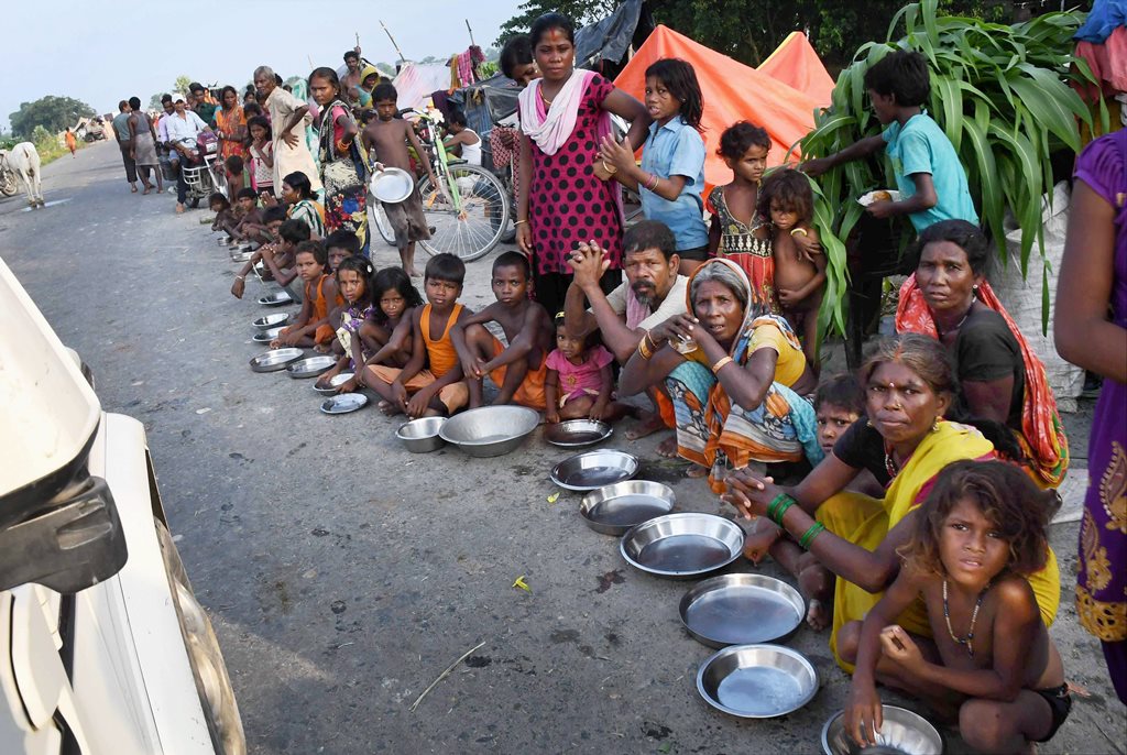 Motihari: Flood-affected people, sheltering along a road, wait for food in Motihari district of Bihar on Thursday. PTI Photo (PTI8 17 2017 000167B)
