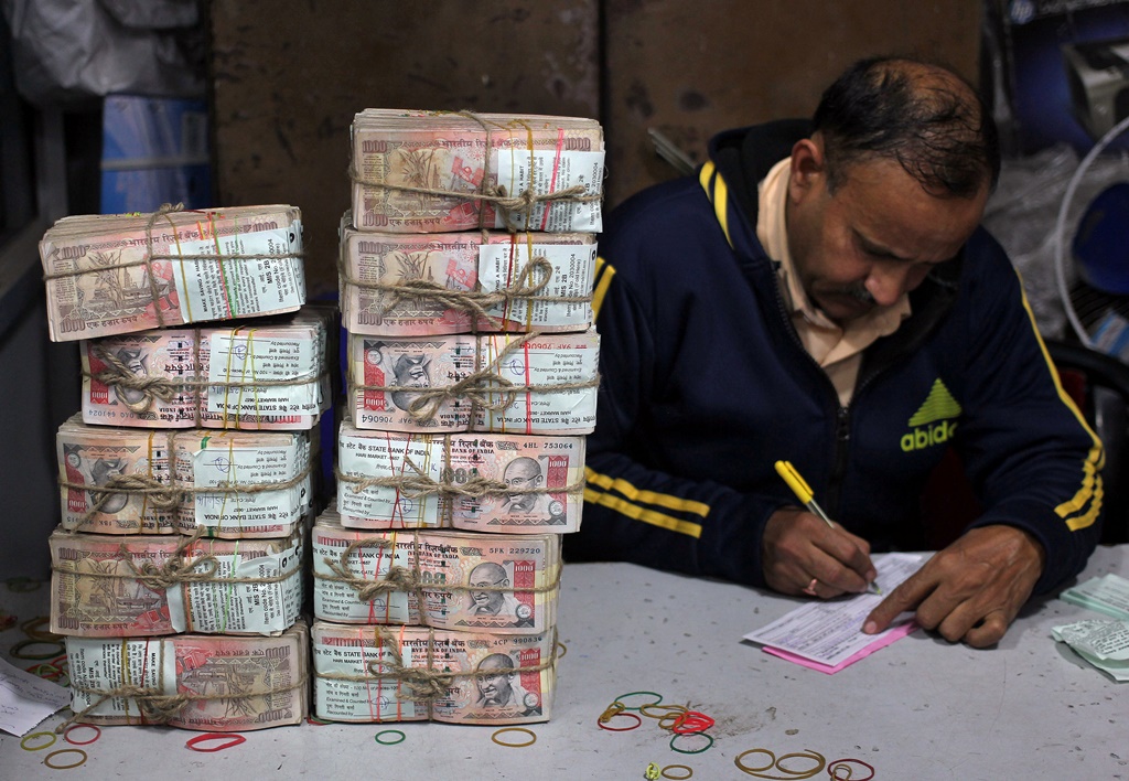A bank employee fills a form after counting stacks of old 1000 Indian rupee banknotes inside a bank in Jammu, November 25, 2016. REUTERS/Mukesh Gupta - RTST9NC