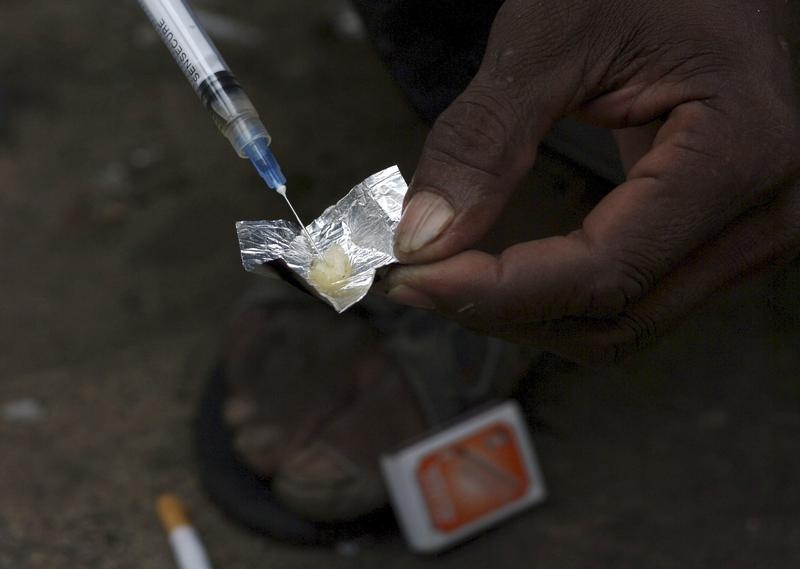 A syringe sucks up a mixture of heroin and water prepared on a foil wrap as addicts shoot up in Stone Town Zanzibar, December 22, 2009. An estimated 4,000-6,000 narcotics addicts use syringes to inject themselves in Zanzibar, a tropical archipelago of one million people, better known for tourism and beach holidays than drug abuse. High rates of HIV among addicts threaten to affect the general population as growth in heroin trafficking through east Africa is making the narcotic more available. Picture taken December 22, 2009. REUTERS/Katrina Manson (TANZANIA - Tags: CRIME LAW HEALTH SOCIETY) - RTR28FHC