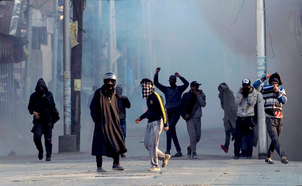 Srinagar: Protesters throw stones on security forces amid tear smoke during a protest against the alleged killing of two youth in Army firing in Shopian district of South Kashmir, in Srinagar on Sunday. PTI Photo by S Irfan (PTI1_28_2018_000158B)