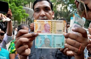 New Delhi: A man shows new currency notes of Rs 200 and Rs 50 outside the Reserve Bank of India in New Delhi on Friday.This is the first time that Rs 200 banknotes were introduced in India. PTI Photo(PTI8_25_2017_000039B)