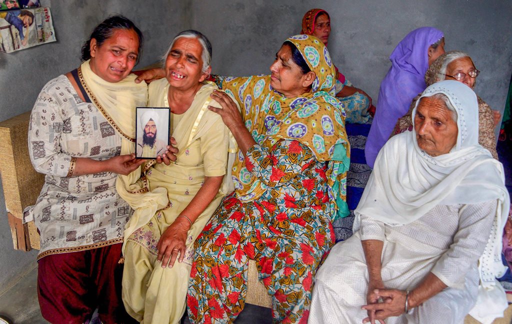 Amritsar: Family members grieve by a portrait of one of the 39 Indian workers feared killed in Iraq, on the outskirts of Amritsar on Tuesday. External Affairs Minister Sushma Swaraj in a statement made at Rajya Sabha today, stated that the 39 bodies exhumed from a mount in Badoosh in Iraq have been identified as those of abducted Indians and will be brought back to India on a special plane. PTI Photo(PTI3_20_2018_000168B)