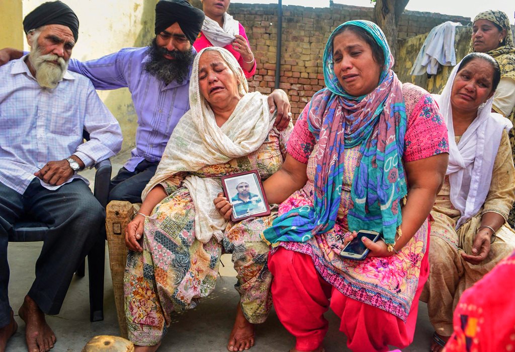 Amritsar: Family members grieve by a portrait of one of the 39 Indian workers feared killed in Iraq, on the outskirts of Amritsar on Tuesday. External Affairs Minister Sushma Swaraj in a statement made at Rajya Sabha today, stated that the 39 bodies exhumed from a mount in Badoosh in Iraq have been identified as those of abducted Indians and will be brought back to India on a special plane. PTI Photo(PTI3_20_2018_000158B)