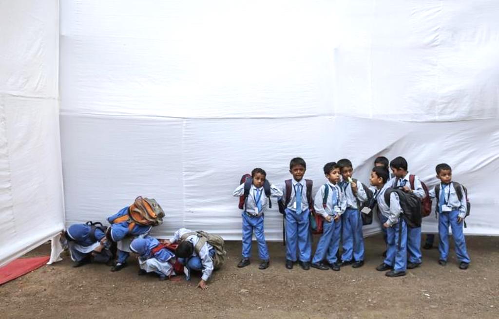 School children try to watch a cultural event through a temporary divider as others wait for their bus at a school in Mumbai January 30, 2014. REUTERS/Danish Siddiqui (INDIA - Tags: EDUCATION SOCIETY)