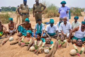 Tiruchirappalli: Farmers representing National South Indian River Link Association lie neck deep in Cauvery river bed with rose garlands to signify 'death' as part of their protest demanding the constitution of Cauvery Management Board in Tiruchirappalli on Friday. PTI Photo (PTI4_6_2018_000206B)