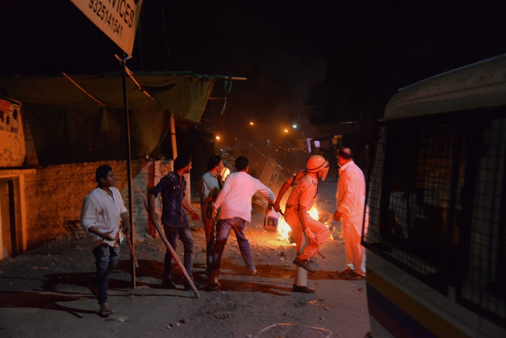 Aurangabad: A police personnel looks as fire is set ablaze due to a communal riot that escalated due to clamping illegal water connection in a religious place in Moti Karanja area of Aurangabad on Friday. PTI Photo (PTI5_12_2018_000047B)