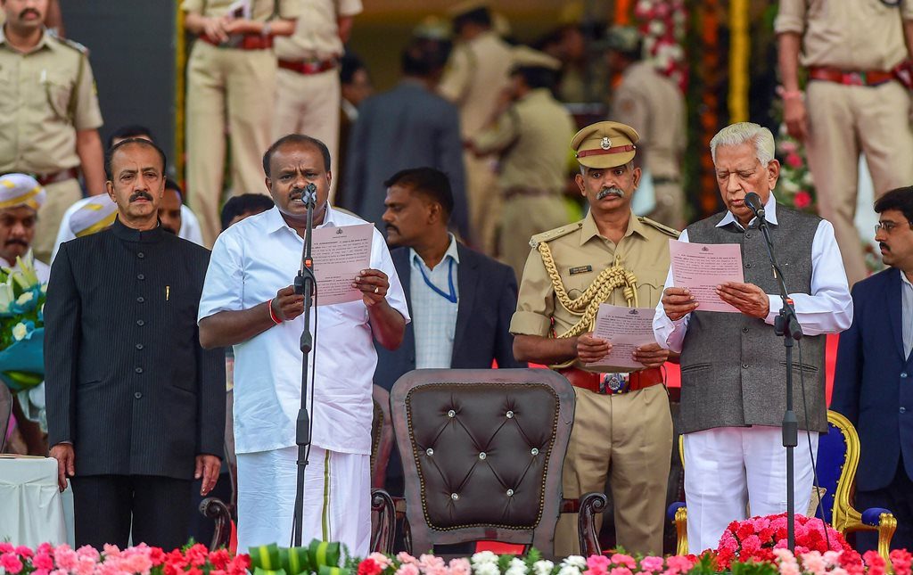 RPT with add info::: Bengaluru: Karnataka Governor Vajubhai Vala administers the oath to JD(S) leader H D Kumaraswamy as Karnataka Chief Minister during the swearing-in ceremony of JD(S)-Congress coalition government, in Bengaluru, on Wednesday. (PTI Photo/Shailendra Bhojak) (PTI5_23_2018_000130B)