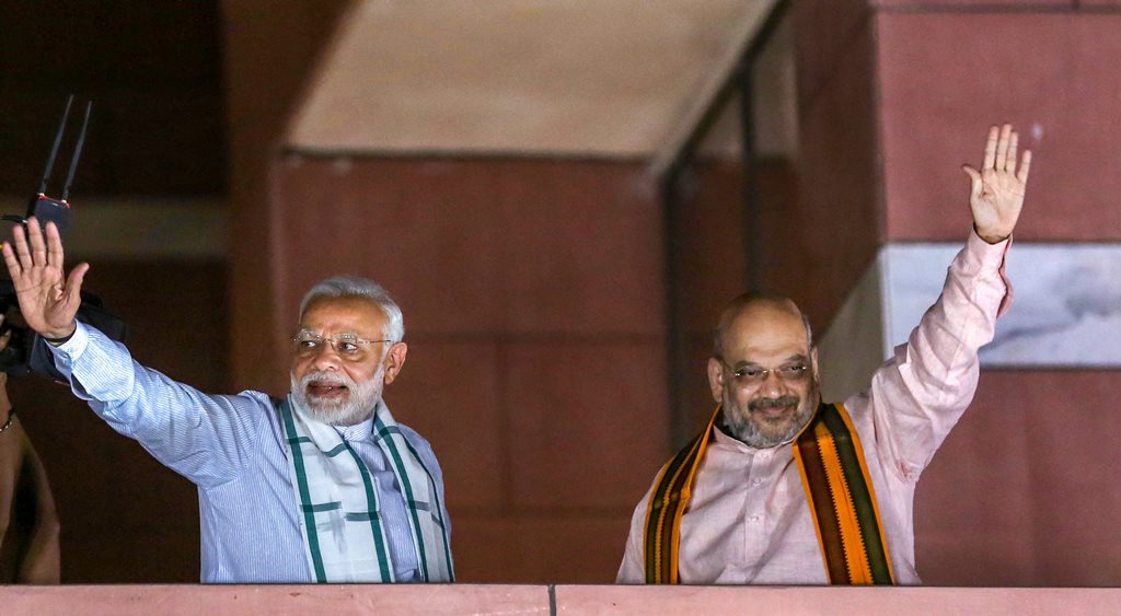 New Delhi: Prime Minister Narendra Modi and BJP President Amit Shah wave to party workers gathered at the party headquarters, after the Karnataka Assembly elections result 2018, in New Delhi, on Tuesday. (PTI Photo) (PTI5_15_2018_000229B)