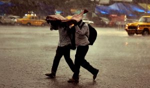 Kolkata: Two men use a plastic sheet to protect themselves, as it rains in Kolkata on Sunday. (PTI Photo / Ashok Bhaumik) (PTI5_13_2018_000096B)
