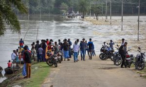 Hojai: Villagers stand near a partially-submerged land in the flood-affected area, of Hojai on Saturday, June 16, 2018. (PTI Photo) (PTI6_16_2018_000155B)