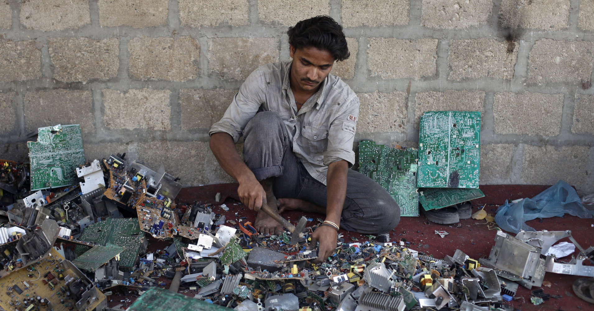 Ali Raza, 21, a scrap worker breaks a computer apart in order to retrieve metal to be used for soldering wires at a makeshift workshop in Karachi April 20, 2011. REUTERS/Athar Hussain (PAKISTAN - Tags: SOCIETY BUSINESS)