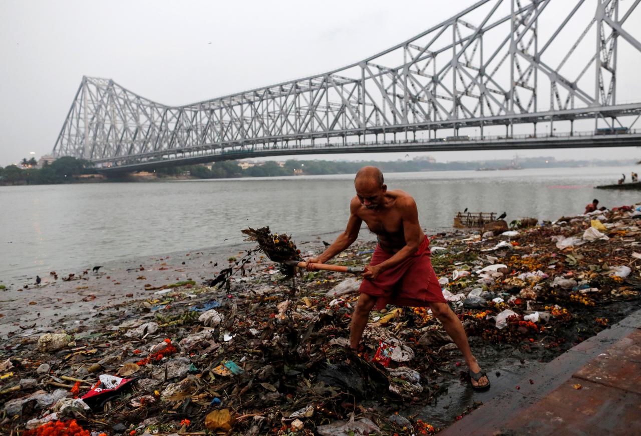 A man cleans garbage along the banks of the river Ganges in Kolkata, India, April 9, 2017. REUTERS/Danish Siddiqui