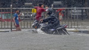 Mumbai: A motorcyclist moves through a waterlooged road during heavy rains, at King Circle in Mumbai on Tuesday, July 10, 2018. (PTI Photo/Shashank Parade) (PTI7_10_2018_000103B)