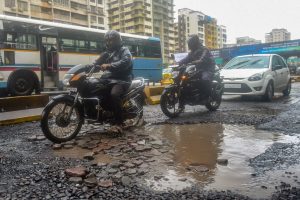 Mumbai: Commuters ride past pot-holes filled road after heavy rainfall, in Mumbai on Monday, July 9, 2018. (PTI Photo/Mitesh Bhuvad) (PTI7_9_2018_000181B)