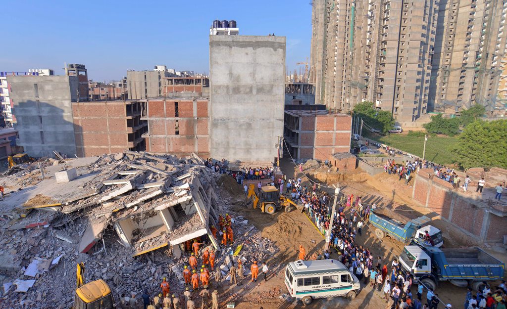 Greater Noida: Rescue workers carry the body of a victim at the site of a collapsed building at Shahberi village, in Greater Noida West on Wednesday, July 18, 2018. A six-storey under-construction building collapsed in Greater Noida, killing at least two persons and trapping several others under the debris. (PTI Photo) (Story no DES49)(PTI7_18_2018_000012B)