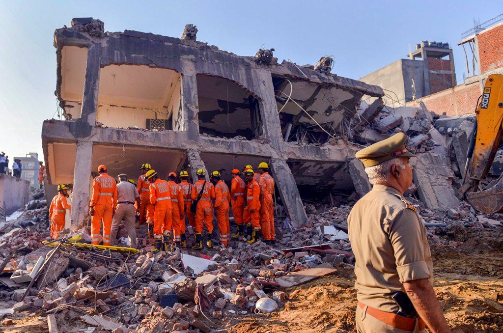 Greater Noida: Rescue workers search for survivors under the debris of a collapsed building at Shahberi village, in Greater Noida West on Wednesday, July 18, 2018. A six-storey under-construction building collapsed in Greater Noida, killing at least two persons and trapping several others under the debris. (PTI Photo) (Story no DES49)(PTI7_18_2018_000014B)