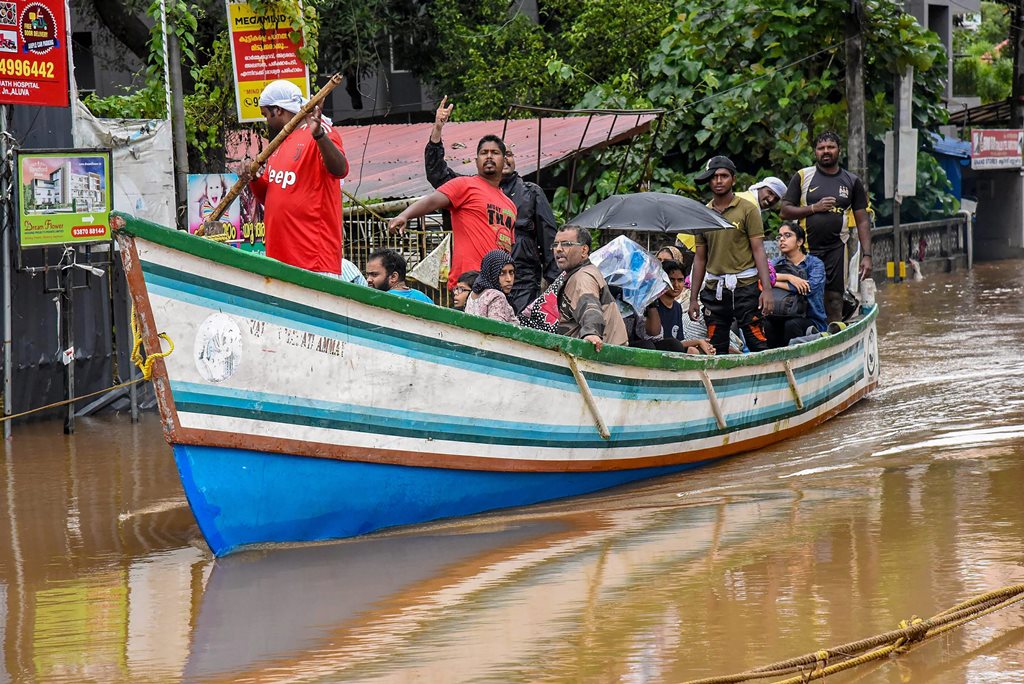 Kochi: Rescue workers row a boat carrying locals who were stranded in floods following heavy monsoon rainfall, in Kochi on Saturday, Aug 18, 2018. (PTI Photo) (PTI8_18_2018_000082B)