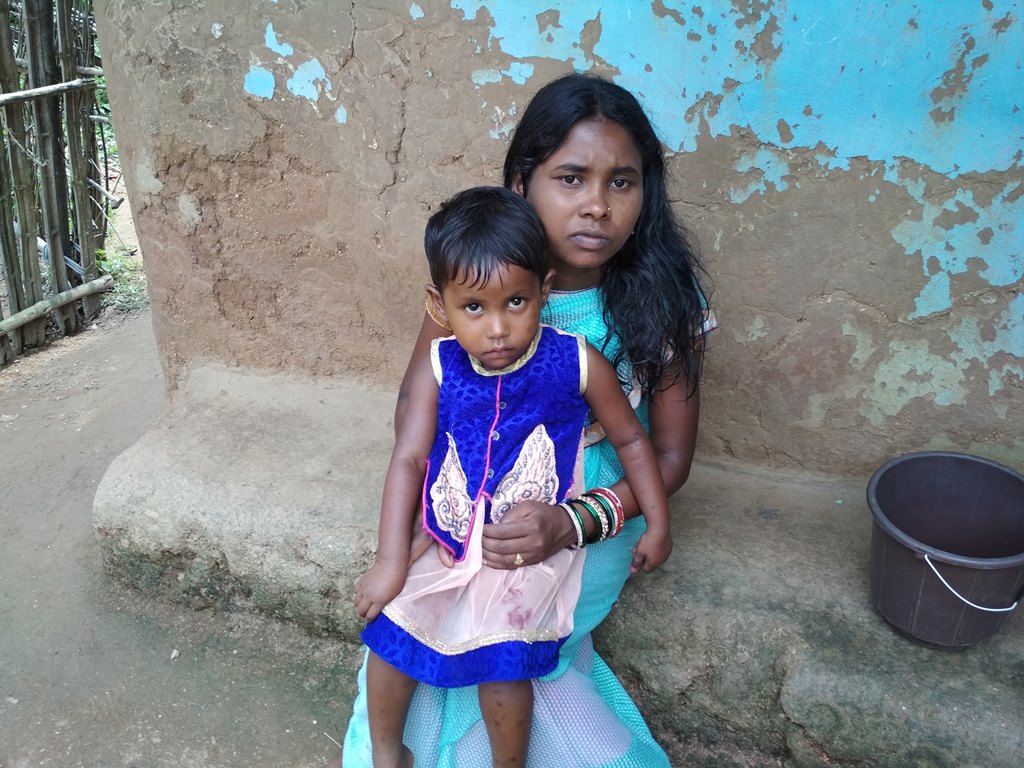 आदिवासी महिला गिरिबाला अपनी बच्ची के साथ. उन्हें इन दिनों पोषाहार नहीं मिल रहा है. (फोटो: नीरज सिन्हा/द वायर) 