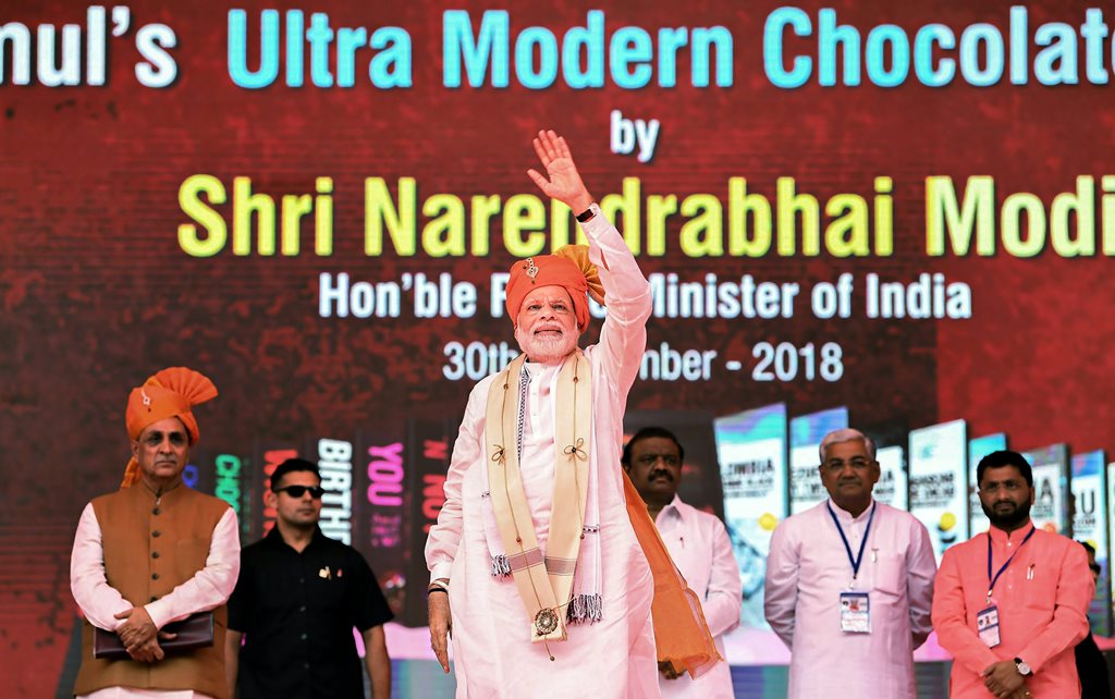 Anand: Prime Minister Narendra Modi at the inauguration of Amul’s ultra-modern Chocolate Plant, in Anand, Gujarat, September 30, 2018. Gujarat Chief Minister Vijay Rupani (L) is also seen. (PIB Photo via PTI) (PTI9_30_2018_000071B)