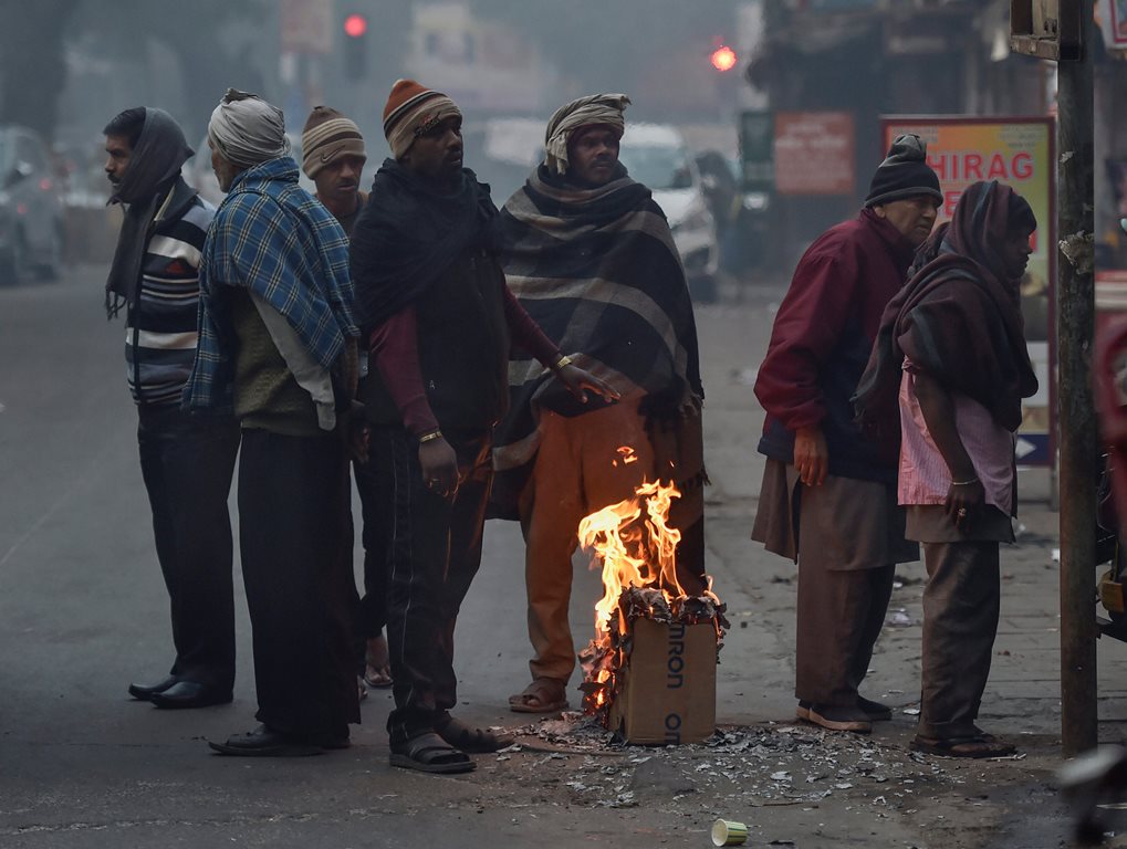 New Delhi: People gather around a makeshift bonfire to warm themselves on a cold, foggy morning, in New Delhi, Sunday, Dec. 23, 2018. (PTI Photo/Ravi Choudhary) (PTI12_23_2018_000065)