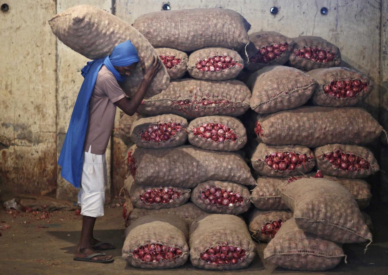A labourer stacks a sack of onions in a storage room at a wholesale vegetable and fruit market in New Delhi July 2, 2014. REUTERS/Anindito Mukherjee