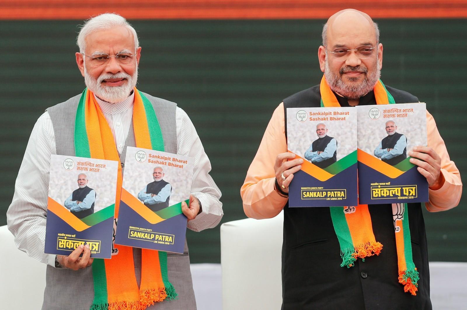 Indian Prime Minister Modi and chief of the ruling party Amit Shah display copies of their party's election manifesto [Adnan Abidi/Reuters]