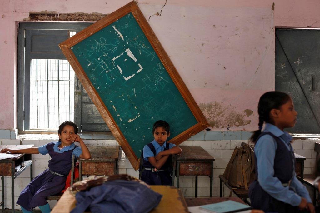 Schoolgirls sit inside their classroom before collecting their free mid-day meals, being distributed by a government-run primary school, in New Delhi May 8, 2013. India may soon pass a new law to give millions more people cheap food, fulfilling an election promise of the ruling Congress party that could cost about $23 billion a year and take a third of annual grain production. The National Food Security Bill, which aims to feed 70 percent of the population, could widen India's already swollen budget deficit next year, increasing the risk to its coveted investment-grade status. REUTERS/Mansi Thapliyal (INDIA - Tags: EDUCATION POLITICS FOOD) - RTXZEKN