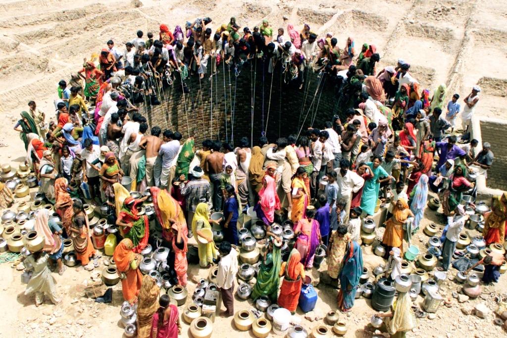 People gather to get water from a huge well in the village of Natwarghad in the western Indian state of Gujarat on June 1, 2003. Natwargadh is in the midst of the worst drought in over a decade. Dams, wells and ponds have gone dry across the western and northern parts of Gujarat forcing people to wait for hours around village ponds for the irregular state-run water tankers to show up as the temperature sores to over 44 degree Celcius. The United Nation's World Environment Day will be celebrated on Thursday with the theme of "Water - Two Billion People are Dying for It". REUTERS/Amit Dave BEST QUALITY AVAILABLE