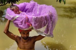 Sitamarhi: A man carries a child in a basket as he wades through a flooded street following incessant rainfall, in Sitamarhi, Friday, July 19, 2019. (PTI Photo)(PTI7_19_2019_000066B)