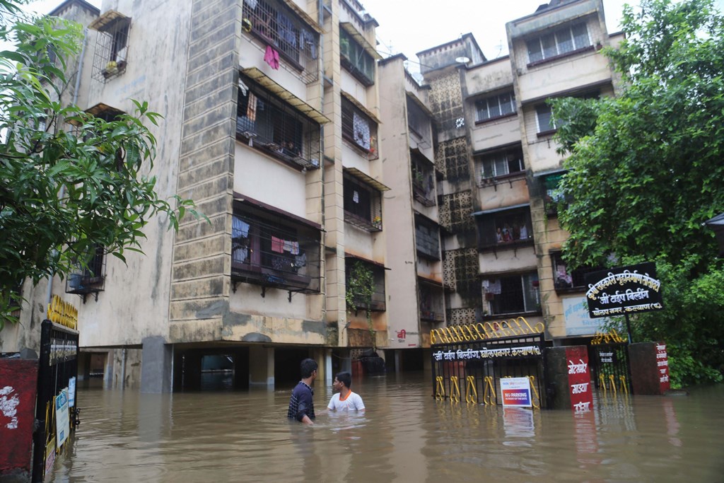 Thane: People wade across a waterlogged street after incessant monsoon rainfall, in Thane, July 27, 2019. (PTI Photo) (PTI7_27_2019_000119B)