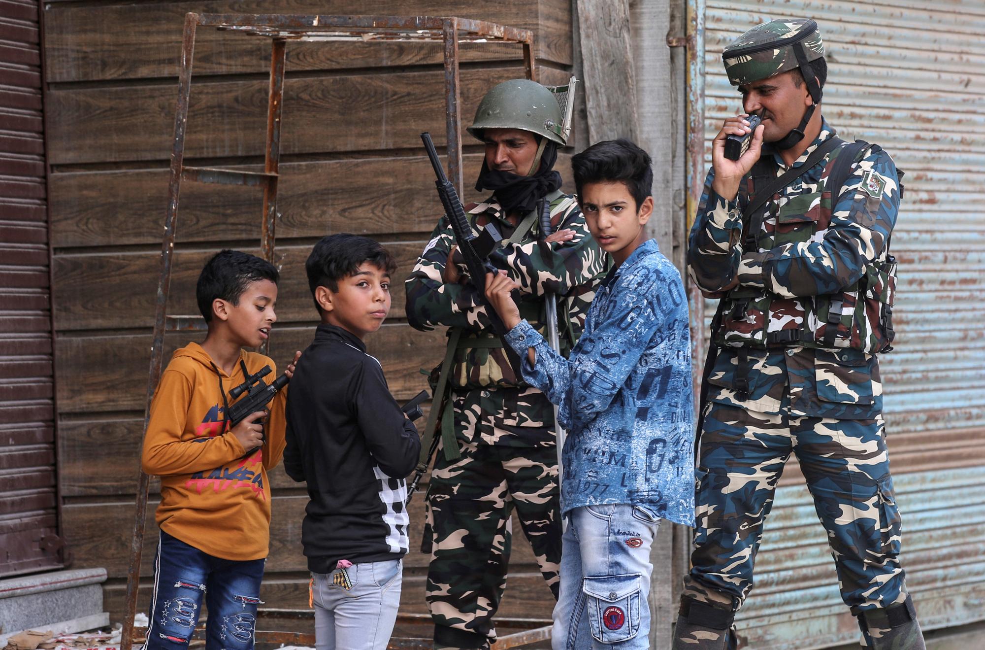 Children play with toy guns next to Indian security force personnel during restrictions after the scrapping of the special constitutional status for Kashmir by the government, in Srinagar, August 13, 2019. REUTERS/Danish Ismail