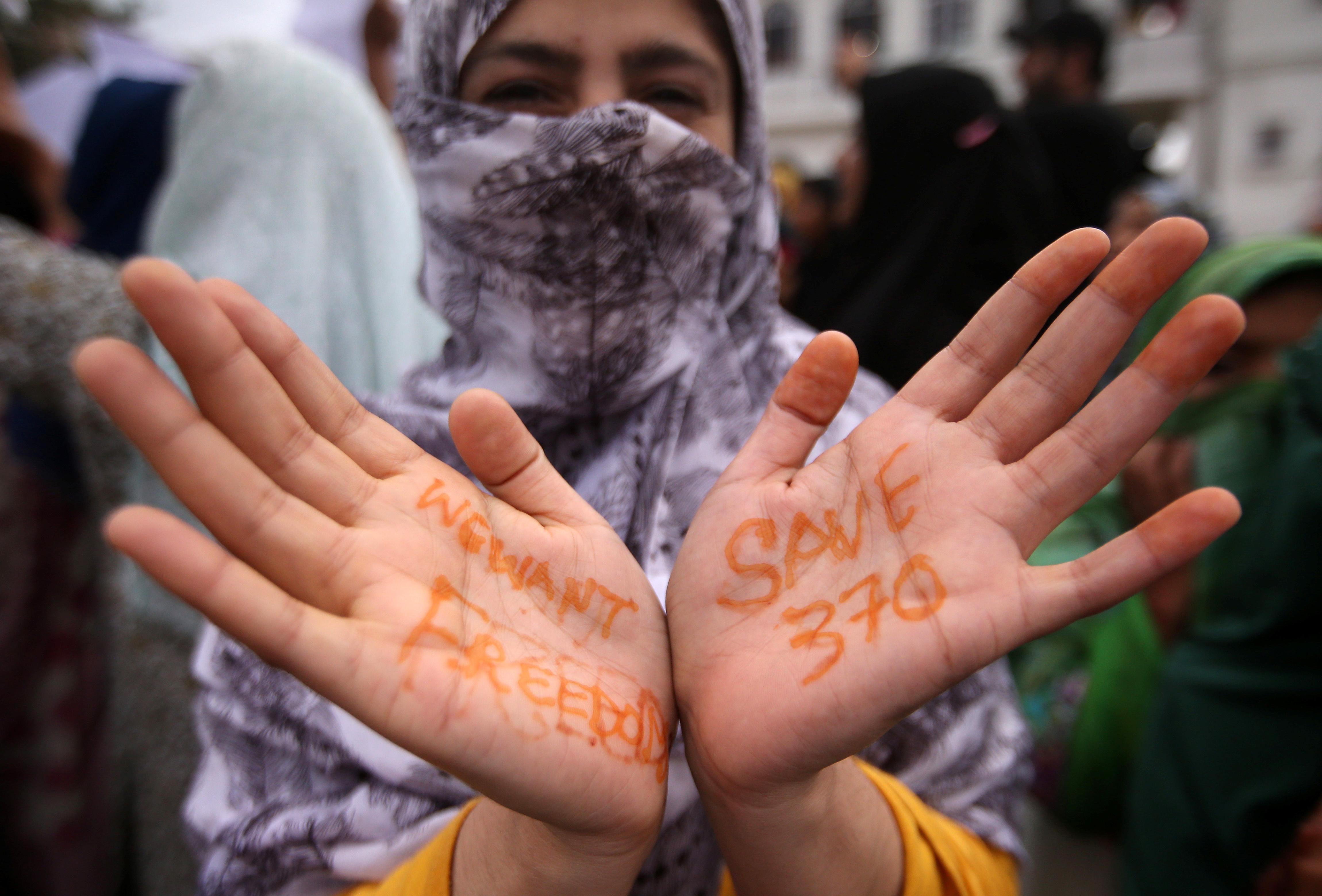 A Kashmiri woman shows her hand with a message as others shout slogans during a protest after the scrapping of the special constitutional status for Kashmir by the Indian government, in Srinagar, August 11, 2019. REUTERS/Danish Siddiqui