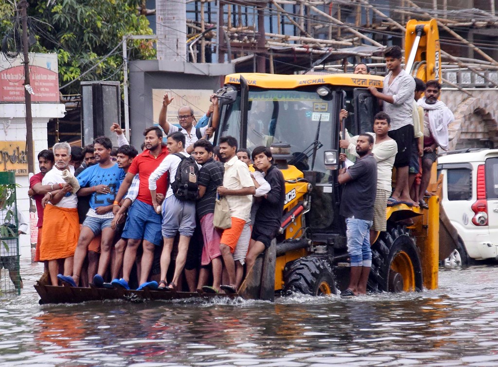 Patna: Residents ride a municipality earth-mover through a flooded street following heavy monsoon rain, in Patna, Monday, Sept. 30, 2019. (PTI Photo)(PTI9_30_2019_000128B)