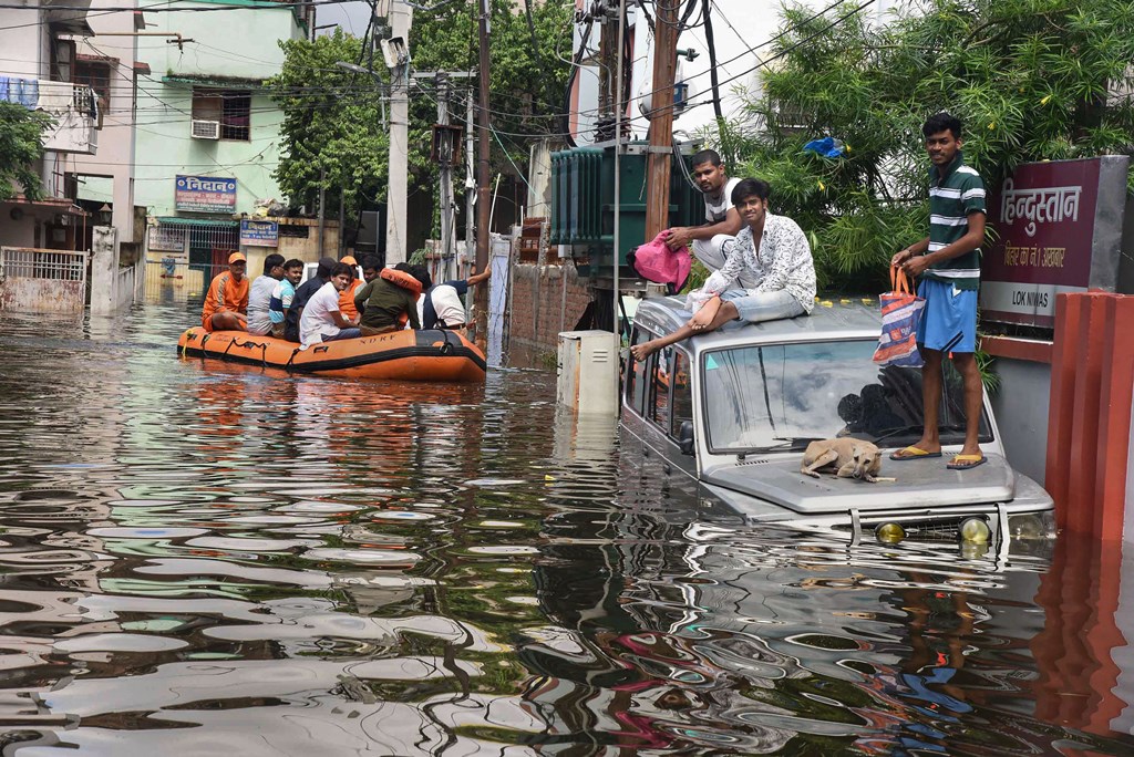 Patna: NDRF personnel rescue flood-affected residents as others sit atop an SUV following heavy monsoon rainfall, in Patna, Tuesday, Oct. 1, 2019. (PTI Photo) (PTI10_1_2019_000270B)