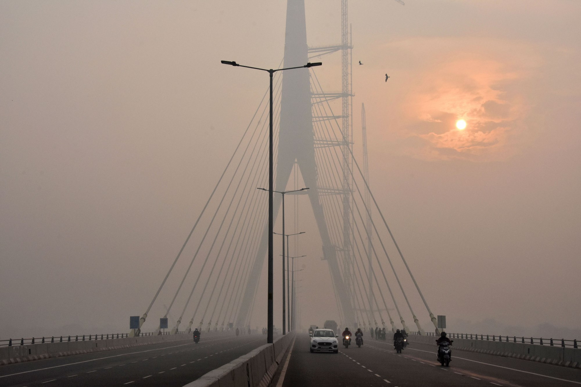 New Delhi: The sun is vaguely seen behind the Signature Bridge amid heavy smog, in New Delhi, Friday, Nov. 15, 2019. A thick layer of toxic smog engulfed Delhi as the pollution level continued to remain in the 'severe' category for the fourth consecutive day. (PTI Photo)